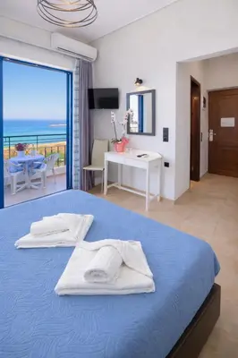 a bedroom with a blue bed with a view of the ocean at Alexis Hotel in Chania Town