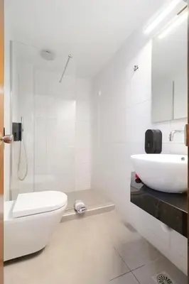 a white bathroom with a toilet and a sink at Alexis Hotel in Chania Town