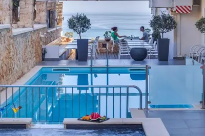 a swimming pool with a view of the ocean at Alexis Hotel in Chania Town