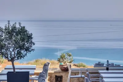a group of chairs and a table with a view of the ocean at Alexis Hotel in Chania Town
