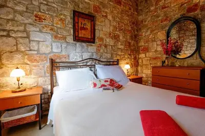 a bedroom with a large white bed and a stone wall at Villa Vicina - In Platanias and 4min by the beach in Chania Town