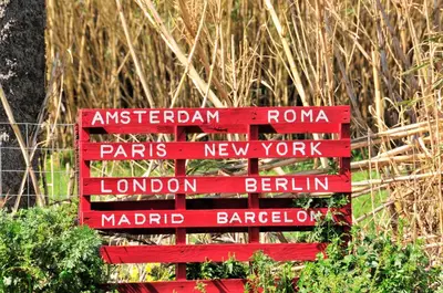 a red wooden sign with different names on it at Cornelia Hippie Magic Bus in Kissamos