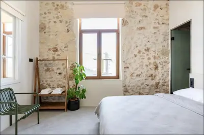 a bedroom with a bed and a chair and a window at PETRA - casa casa group in Chania Town