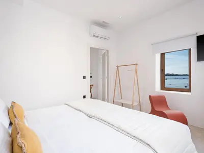 a white bedroom with a bed and a chair at ALS - casa casa group in Chania Town