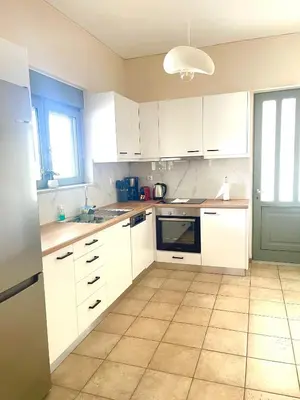 a kitchen with white cabinets and a tile floor at Blue Port in Chania in Souda