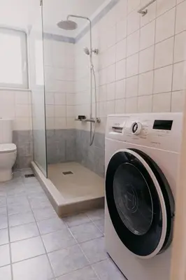 a washing machine in a bathroom with a shower at Blue Port in Chania in Souda