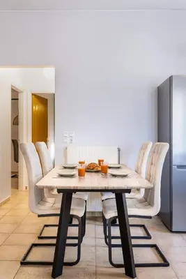 a dining room table with white chairs and a refrigerator at Blue Port in Chania in Souda