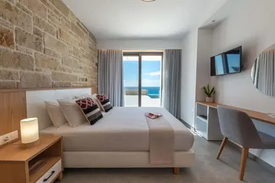 a bedroom with a large bed with a stone wall at Actea Seaview Villas I 