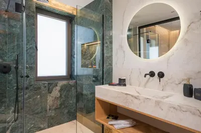 a bathroom with a shower and a sink and a mirror at Villa Ekphrasis with sea view and jacuzzi in Ravdhoúkha