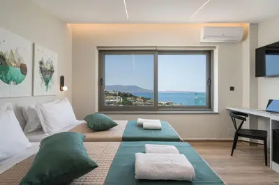 a bedroom with a bed with a desk and a large window at Villa Ekphrasis with sea view and jacuzzi in Ravdhoúkha