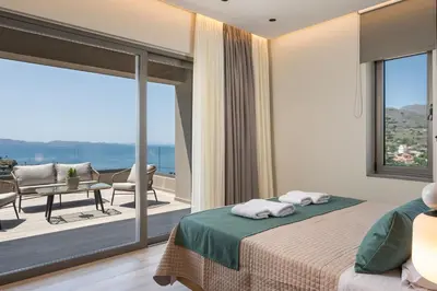 a bedroom with a bed and a balcony with a view at Villa Ekphrasis with sea view and jacuzzi in Ravdhoúkha