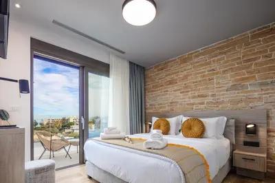 a bedroom with a large bed with a brick wall at Oinolithos Luxury Villas in Kalamaki Chanion