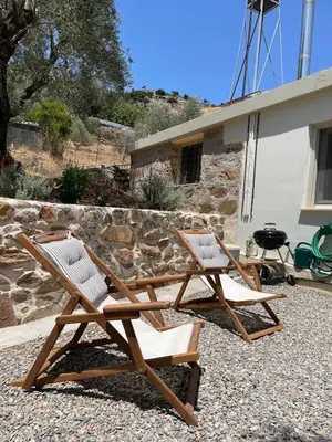 two wooden chairs sitting next to a house at DOLONAS Cosy House in Aliyoí