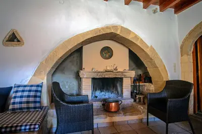 a living room with a fireplace and a couch and chairs at Villa Polirinia in Kissamos