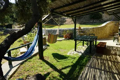 a hammock in a backyard with a table and a fence at Elpida Country House -Paleochora-Anidri in Palaiochóra