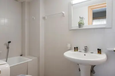 a white bathroom with a sink and a mirror at Hermes Hotel in Kissamos
