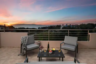 two chairs and a table on a balcony with a sunset at The Cozy Nook in Chorafakia