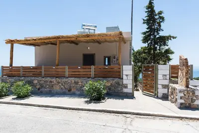 a house with a wooden fence next to a street at Villa Olvía in Sfakiá