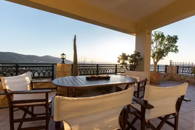 a table and chairs on a porch with a view of the ocean at Falasarna's Sunset Home in Falasarna