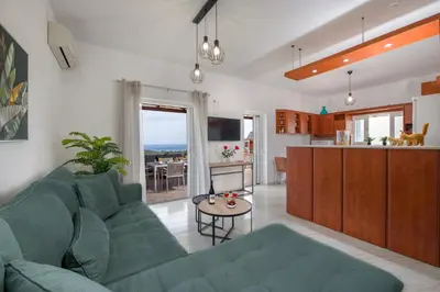 a living room with a green couch and a kitchen at Marakas Winery Family House in Xamoudhokhórion