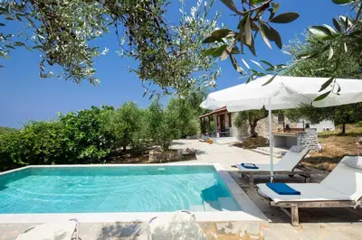 a swimming pool with two chairs and an umbrella at Fortino Villa in Chorafakia