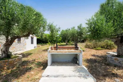 a bench sitting in the middle of a field with trees at Fortino Villa in Chorafakia