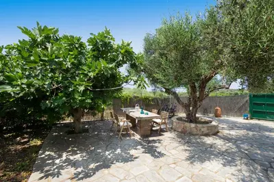 a patio with two trees and a table and chairs at Fortino Villa in Chorafakia