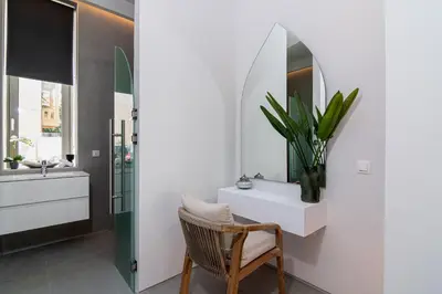 a bathroom with a white vanity and a chair and a mirror at Perla Dream Luxury Villa in Chania Town