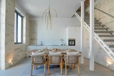 a dining room with a table and chairs and a staircase at Perla Dream Luxury Villa in Chania Town