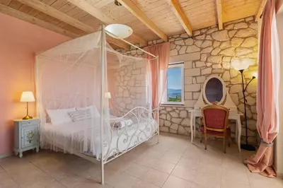 a bedroom with a canopy bed and a chair at Villa Rea Chania in Argoulidhés