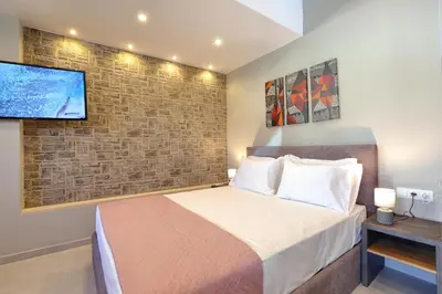 a bedroom with a bed and a tv on a brick wall at Mirma Halepa superior studio in Chania Town