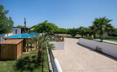 a resort with a swimming pool and palm trees at Eleni Residence by the sea in Ropanianá