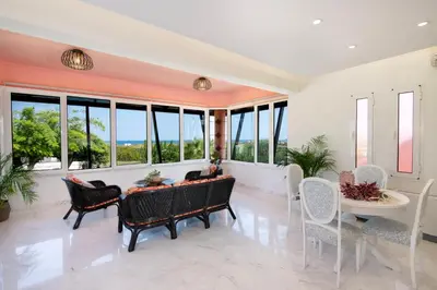 a living room with a table and chairs and windows at Eleni Residence by the sea in Ropanianá