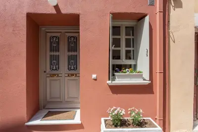 a pink building with a door and flowers in a window at House of Sirri in Chania Town