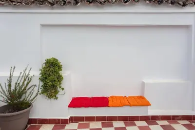 a white wall with three colorful pillows on a bench at House of Sirri in Chania Town