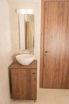 a bathroom with a sink and a mirror on a wooden cabinet at Fanouria's home in Kalleryianá