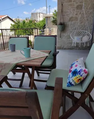 a patio with a wooden table and chairs with a pillow at Fanouria's home in Kalleryianá
