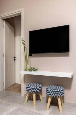 a living room with two stools and a tv on a wall at Eva Cozy Apartment in Chania Town