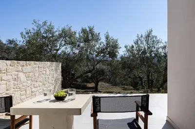 a table and chairs on a patio with trees at Villa Kafkales Maleme - Heated Pool in Maleme