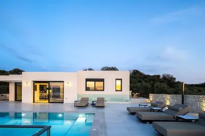 a villa with a swimming pool and lounge chairs at Villa Kafkales Maleme - Heated Pool in Maleme