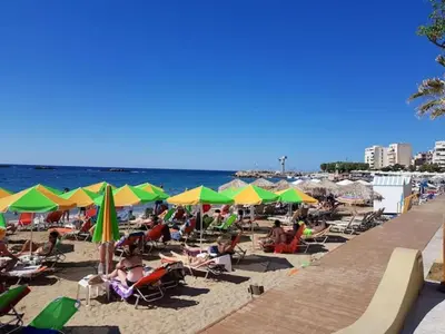 a beach with people sitting in chairs and umbrellas at Sun Beach Apartments in Chania 09 11 in Chania Town