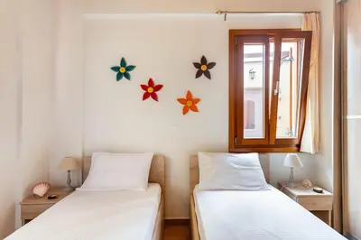 two beds in a room with a window and flowers on the wall at Cozy house in the old town in Chania Town