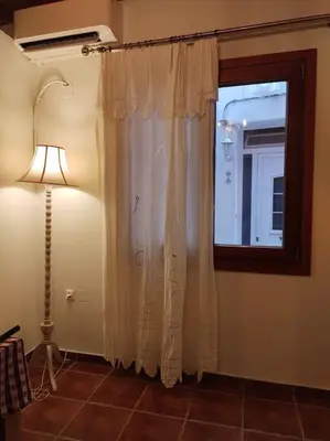 a room with a window with a curtain and a lamp at Cozy house in the old town in Chania Town