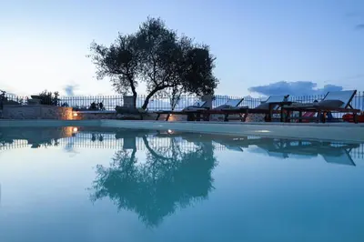 a swimming pool with a tree and some chairs at Heliopetra Lux Villa with private Pool in Varípetron