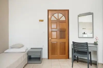 a bedroom with a bed and a desk and a door at Kristina Stelios Apartment in Plataniás