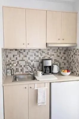 a kitchen with white cabinets and a sink at Kristina Stelios Apartment in Plataniás