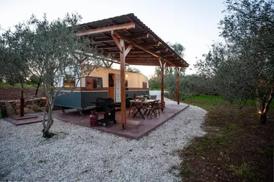 a rv with a table and a grill in a yard at Onar Camper in Liyidhés