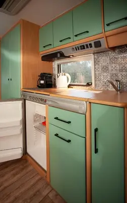 a kitchen with green cabinets and an open refrigerator at Onar Camper in Liyidhés