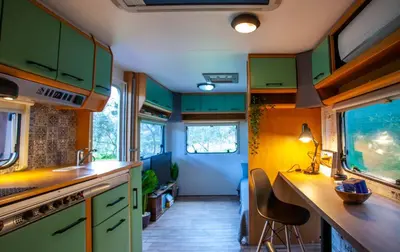a kitchen with green cabinets and a table and chairs at Onar Camper in Liyidhés