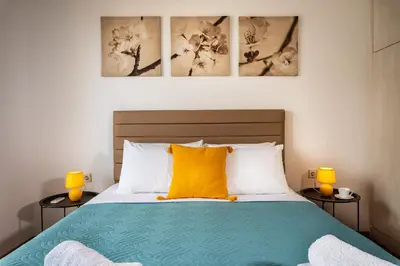 a bedroom with a bed with a yellow pillow and two lamps at Central apt. with parking - 3 min from old port in Chania Town